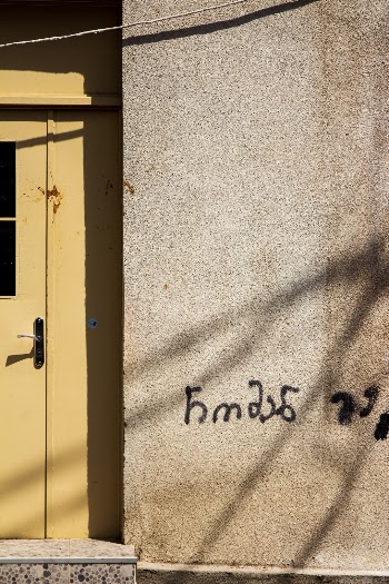 Cement wall with shadows and yellow door.