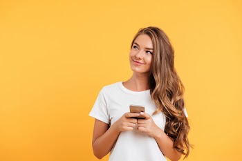 Cheerful cute beautiful young woman chatting by mobile phone Free Photo