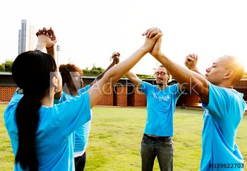 Cheerful volunteers holding hands outdoors