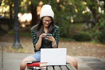 Cheerful woman using mobile phone while sitting on bench