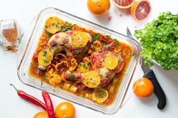 Chicken legs with tomatoes, peppers and oranges 
