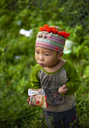 Child Eating Chips While Standing in Green Field