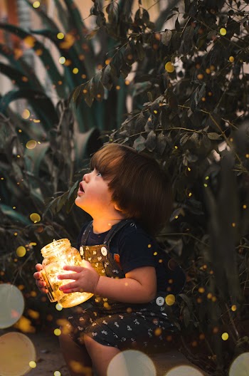 Child Holding Clear Glass Jar With Yellow Light