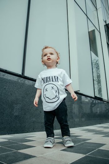 child in Nirvana shirt standing near building