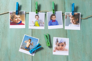 Child photographs hanging on a clothesline in wooden background