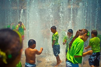 Children in Green T-shirts Bathing on Water Fountain