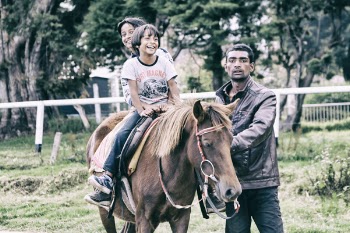 Children Riding Horse With Adult Guiding