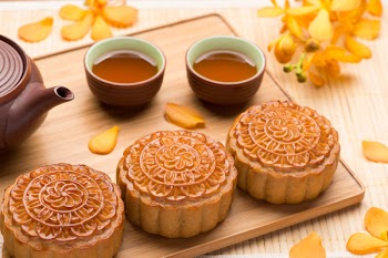 Chinese mid autumn festival foods. Traditional mooncakes on table setting with teacup.