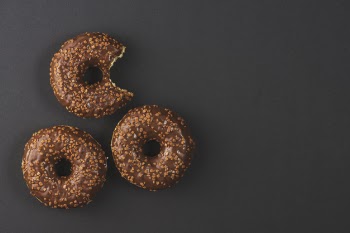 Chocolate donuts with bite mark on black background