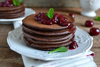 chocolate pancakes with berry jam for breakfast on a wooden background