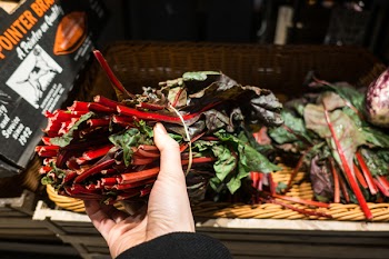Choosing red swiss chard in a grocery store 
