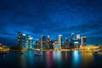 city buildings beside body of water under cloudy sky