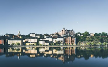 city buildings near body of water under blue sky