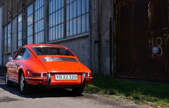 Classic Orange Coupe Near Brown Concrete Building