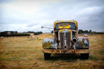 classic yellow vehicle on grass field under cloudy sky