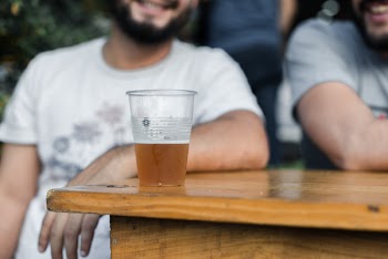 Clear Disposable Cup With Brown Liquid Inside on Top of Brown Table Selective Focus Photography