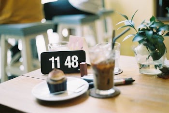 clear drinking glass beside round white ceramic plate on brown wooden table