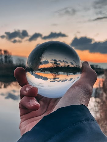 Clear Glass Ball With Reflection Of Body Of Water During Golden Hour