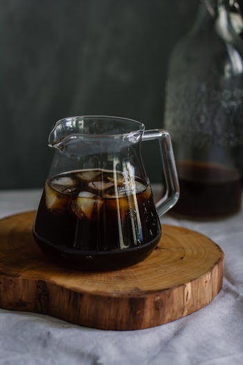 Clear Glass Pitcher With Cola and Ice on Wooden Chopping Board