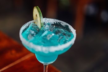 clear margarita glass with cyan liquid and lime slice
