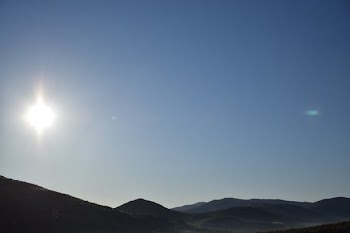 Clear Sky And Glaring Sun Over Hillside