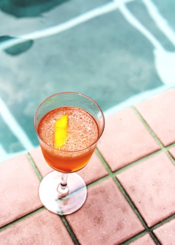 Clear Stemmed Glass With Orange Beverage on Brown Surface Beside Pool Close-up Photography