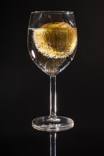 Clear Wine Glass Filled With Clear Beverage With Yellow Round Fruit