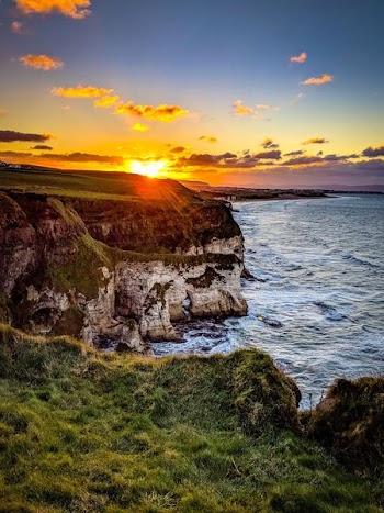 cliff beside body of water during sunset