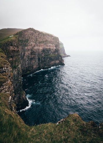Cliff Beside Body of Water With Fog