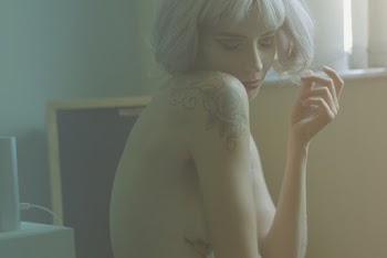 Close Of A Naked  Blonde Woman With Tattoos On Her Shoulder And Side