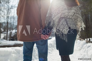 Close up affectionate couple holding hands on snowy footpath