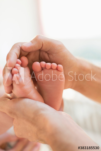 Close up hands of father cupping tiny feet of baby son