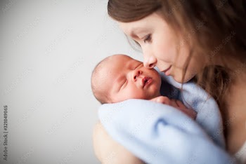 Close up of beautiful young woman holding adorable baby wrapped in blue blanket. Cute child sleeping in mother arms. Isolated on white studio background. Concept of motherhood.