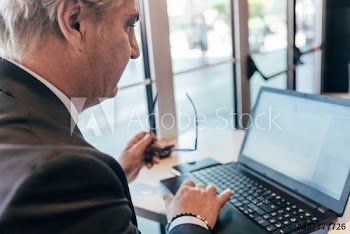 Close up of mature businessman working on laptop in bar