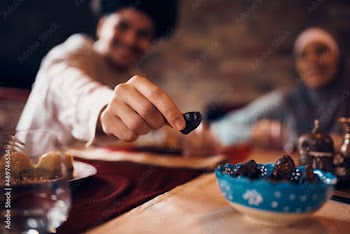 Close-up of Middle Eastern man eats date during dessert at home.