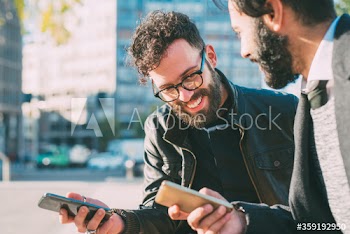 Close up of smiling businessmen using smartphone outdoors