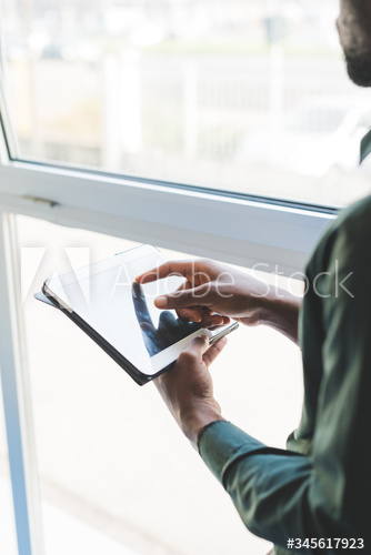 Close up of young businessman using digital tablet indoors