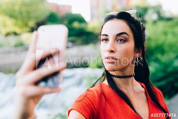 Close up of young woman taking selfie with smartphone outdoors