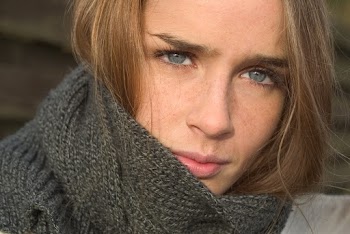 Close-up photo of a brown haired woman wearing a grey  scarf