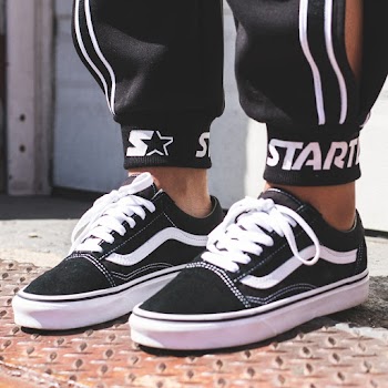 Close-up Photo of a Person in a Pair of Black Vans Sneakers and Black Starter Sweatpants