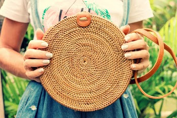 Close-up Photo of a Round Brown Rattan Bag Held by Woman