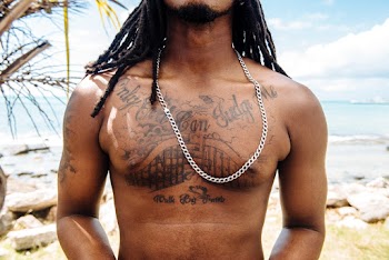 Close-up Photo of Bear-chested man With Tattoos Posing by the Beach