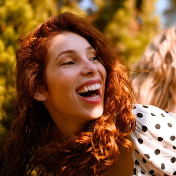 Close-up Photo of Laughing Woman in White and Black Polka-dot Top