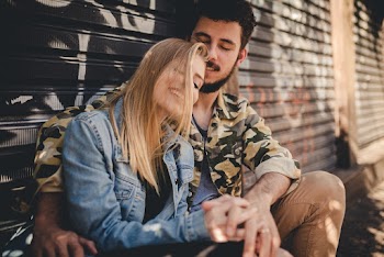 Close-up Photo of Man Hugging Woman While Sitting In Front of Roll Up Doors