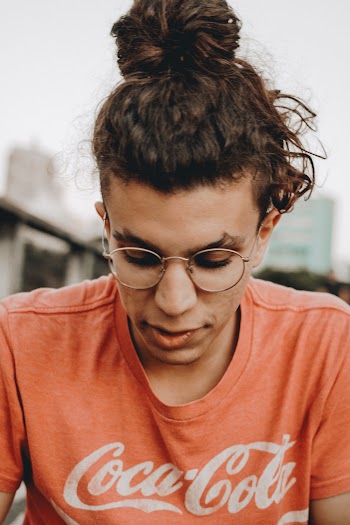 Close-up Photo of Man in Red Coca-cola T-shirt and Glasses Looking Down