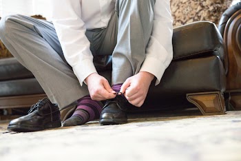 Close-up Photo of Man Sitting on Sofa Tying His Laces