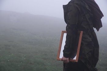 Close Up Photo of Person in a Jacket Holding Brown Wooden Framed Mirror