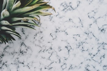 Close-up Photo of Pineapple Crown on Marble Surface
