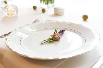 Close-up Photo of Pink and Purple Flower on Scalloped Edge White Ceramic Plate Beside Silver Fork and Spoon on Table