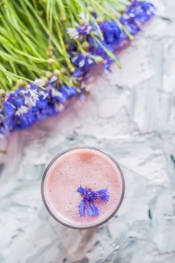 close-up photo of purple flower on pink liquid